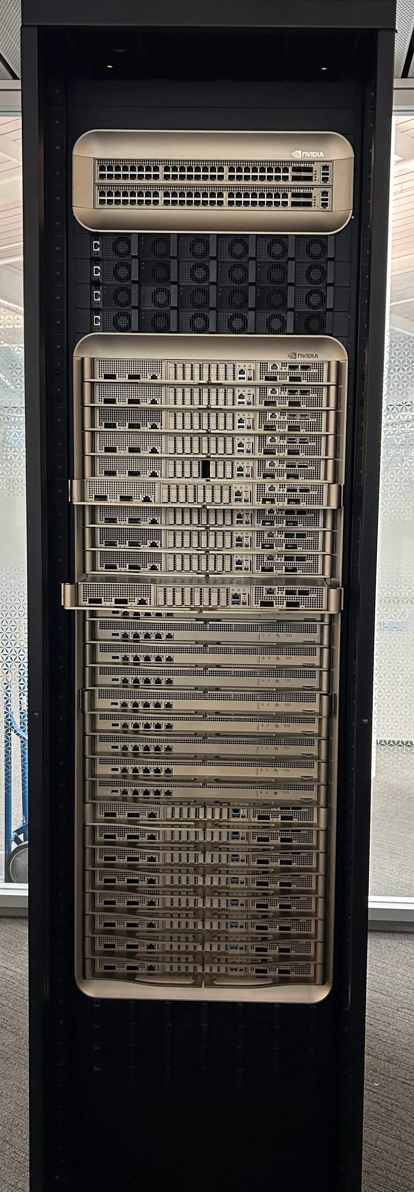 Tall DGX GB200 cabinet with rows of gold-colored compute and switch trays and NVIDIA branding