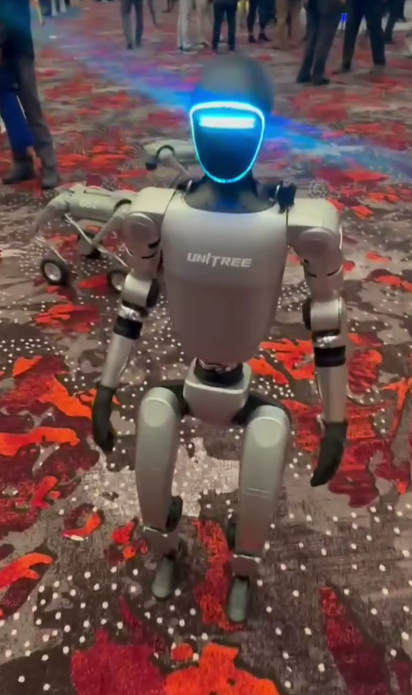 Unitree G1 humanoid robot with a silver body and illuminated face panel.