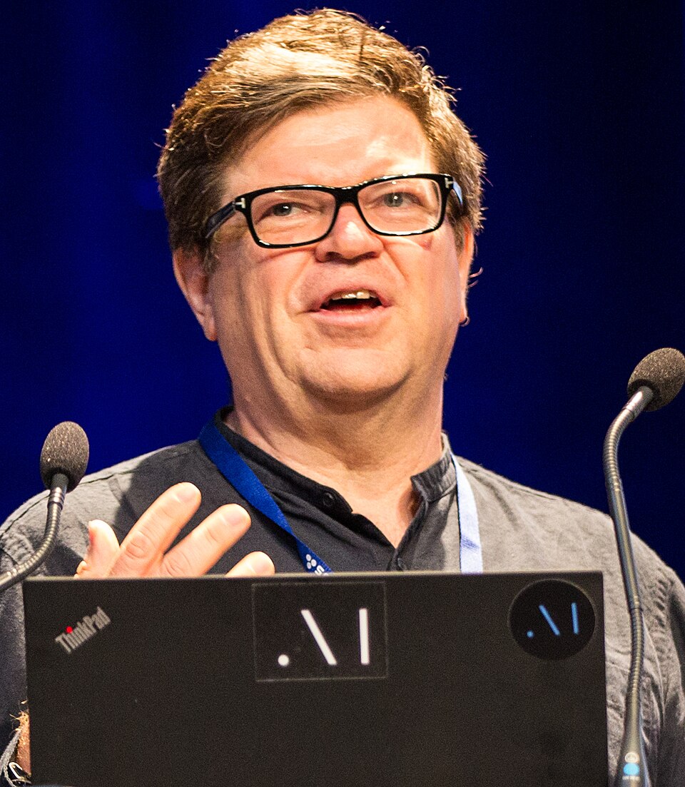 Yann LeCun speaking behind a laptop and microphones