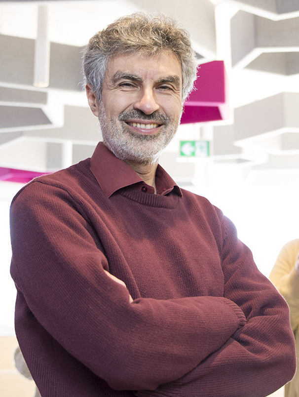 Yoshua Bengio smiling with folded arms in a burgundy sweater
