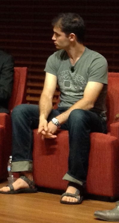 Ilya Sutskever seated in a red chair wearing a green T-shirt