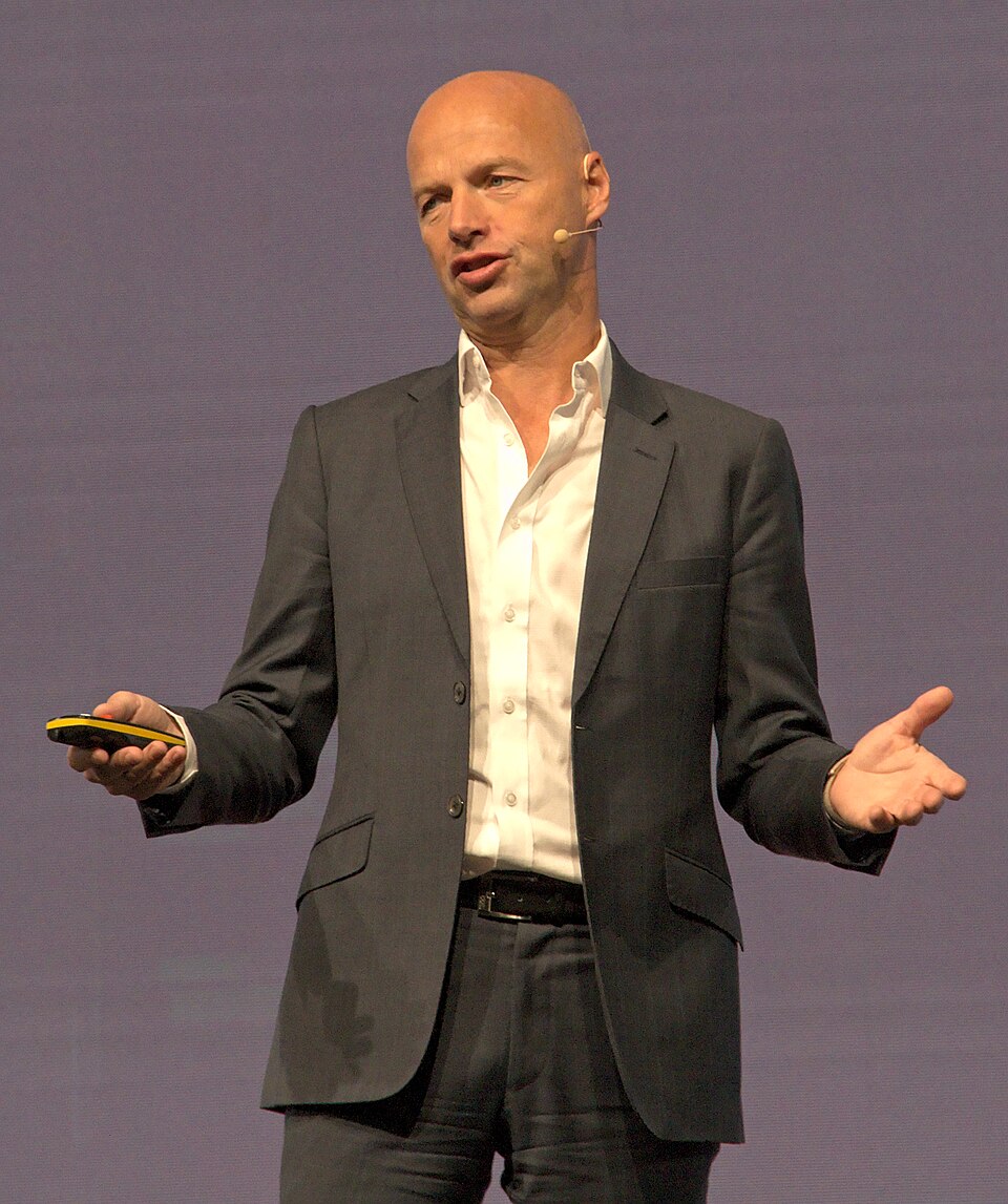 Sebastian Thrun speaking with a headset microphone and holding a presentation remote