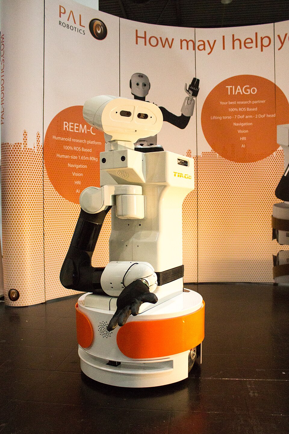 White and orange single-arm TIAGo robot with a wheeled base and sensor head at RoboCup 2016