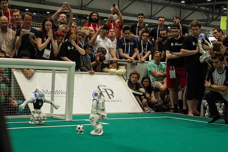 Small humanoid robots playing soccer on a green field at RoboCup 2016